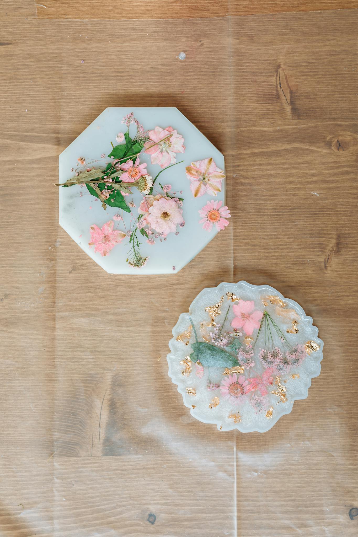 Top view of handmade epoxy resin decor with pink flowers on a wooden table. Perfect for elegant home styling.