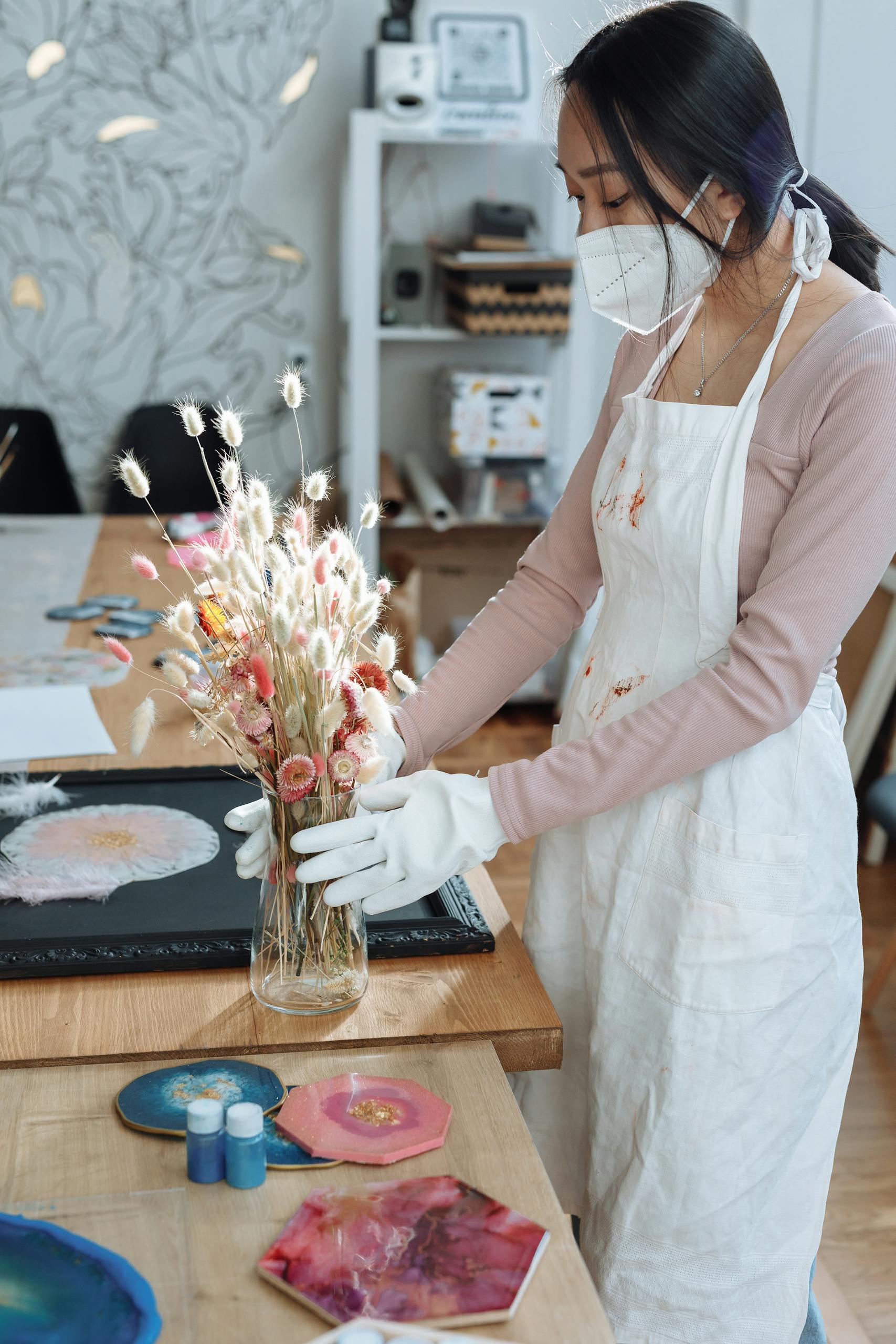 Artiste arrangeant des fleurs sechees pour creation en resine dans un studio professionnel