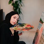 Young woman artist painting with watercolors on a canvas indoors.